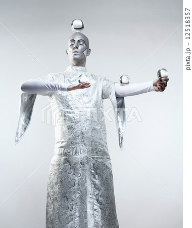 Magician with Glass Balls in Stage Makeup and Costume 12518357