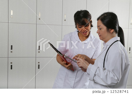 Nurse highlighting a point to lady doctor. Nurse highlighting a point to lady doctor. 12528741