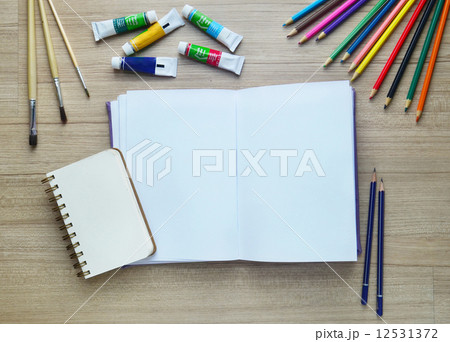 Blank paper, Acrylic paint and colorful pencils on the wood tabl 12531372