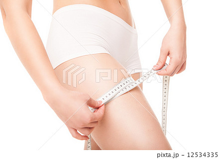 Slimming woman measuring thigh with tape Slimming woman measuring thigh with tape 12534335