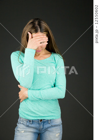model isolated on plain background ashamed hiding face in hand 12550602