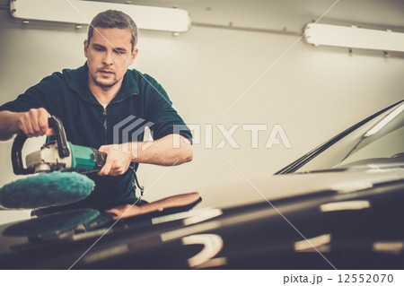 Man on a car wash polishing car with a polish machine Man on a car wash polishing car with a polish machine 12552070