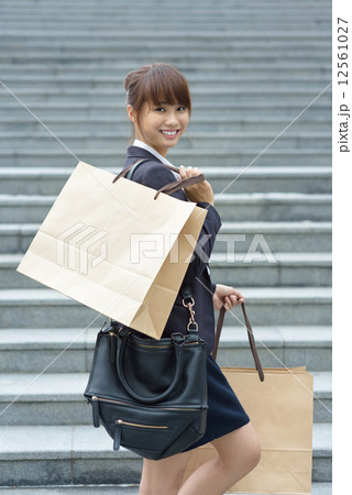 One young Chinese office lady carrying shopping bags in front of steps 12561027
