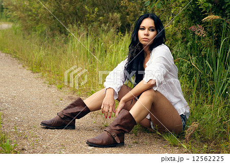 Sexy girl in denim shorts and white shirt sitting by the country 12562225