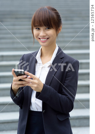 One young Chinese office lady using smart phone in front of steps One young Chinese office lady using smart phone in front of steps 12565734