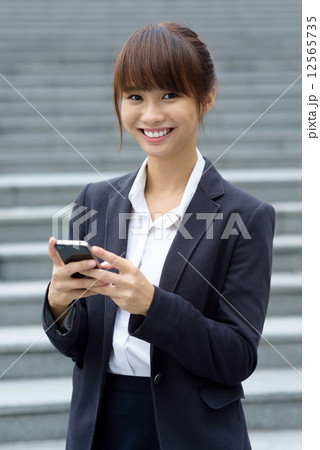 One young Chinese office lady using smart phone in front of steps 12565735