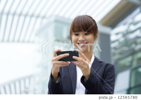 One young Chinese office lady using smart phone in front of office building One young Chinese office lady using smart phone in front of office building 12565780