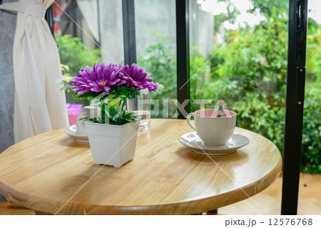 Coffee mug and flower pot on wooden table. 12576768