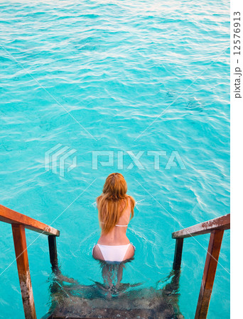 Maldives. .Young sports woman swims from steps of villa on water. 12576913