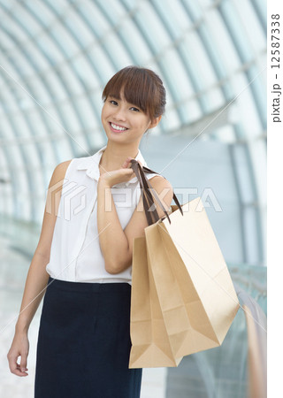 One young Asian Chinese office lady with shopping bags inside a mall 12587338