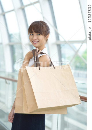 One young Asian Chinese office lady with shopping bags inside a mall One young Asian Chinese office lady with shopping bags inside a mall 12587339
