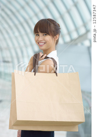 One young Asian Chinese office lady with shopping bags inside a mall One young Asian Chinese office lady with shopping bags inside a mall 12587347