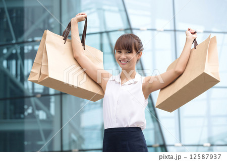 One young Asian Chinese office lady showing her shopping buys outside of mall One young Asian Chinese office lady showing her shopping buys outside of mall 12587937
