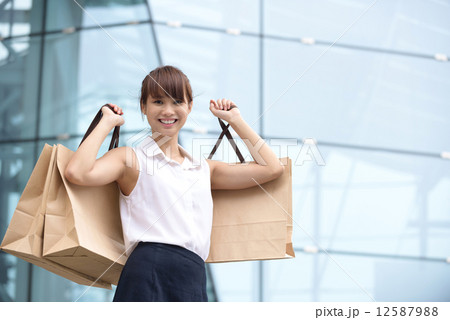 One young chinese shopaholic with her shopping buys in front of glass building mall 12587988