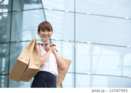 One young chinese shopaholic with her shopping buys in front of glass building mall One young chinese shopaholic with her shopping buys in front of glass building mall 12587993