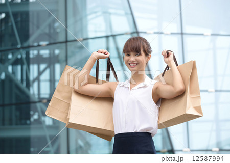 One young chinese shopaholic with her shopping buys in front of glass building mall 12587994