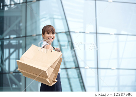 One young chinese shopaholic with her shopping buys in front of glass building mall 12587996