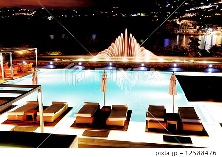 Swimming pool with fountain in night illumination at the luxury 12588476