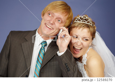 Happy bride and groom is congratulated by phone Happy bride and groom is congratulated by phone 12589270