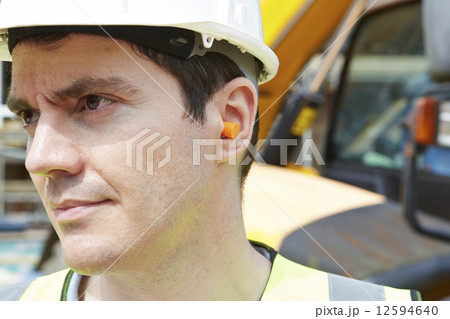Construction Worker Wearing Protective Ear Plugs 12594640