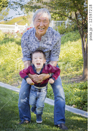 Chinese Grandpa Having Fun with His Mixed Race Grandson Outside 12597218