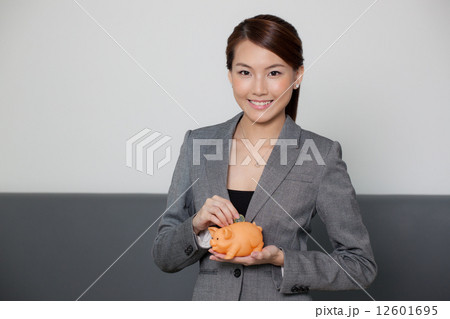 Businesswoman holding piggy bank and coin  12601695