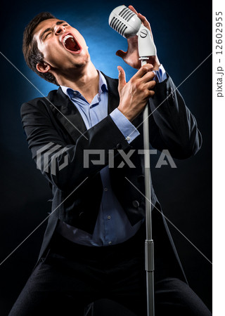 Man in elegant black jacket and blue shirt singing 12602955