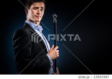 Man in elegant black jacket and blue shirt holding cane Man in elegant black jacket and blue shirt holding cane 12602987