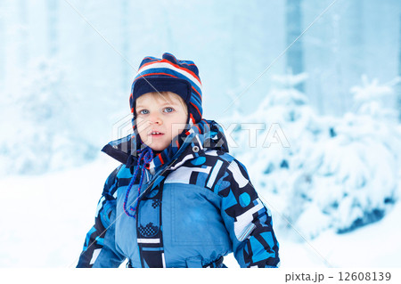 Adorable kid boy having fun with snow outdoors Adorable kid boy having fun with snow outdoors 12608139