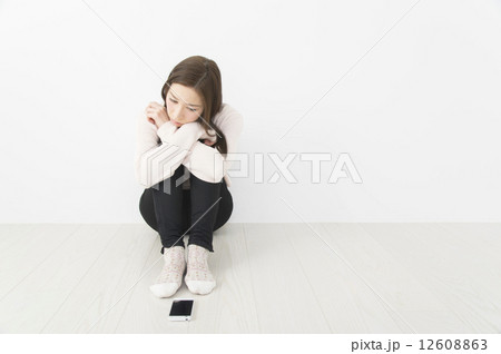 スマホに連絡が来るのをじっと待つ若い女性 12608863