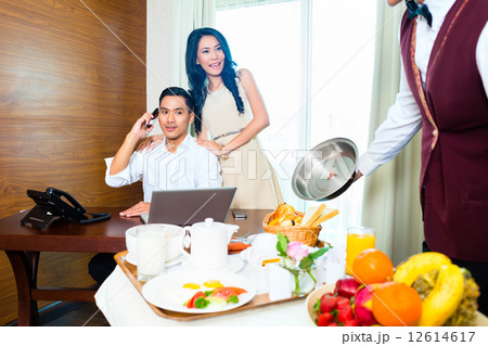 Asian room service waiter serving in hotel room Asian room service waiter serving in hotel room 12614617