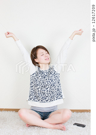 あぐらをかいて座り気持ちよさそうに伸びをする若い女性の写真素材