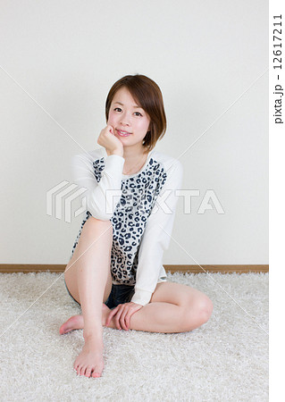 立膝をついて座る笑顔の若い女性の写真素材