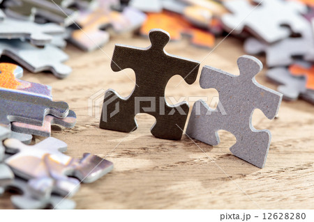 Black and Grey Jigsaw Puzzle Pieces on Table Black and Grey Jigsaw Puzzle Pieces on Table 12628280