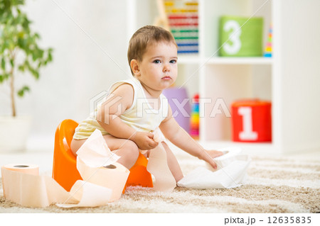 kid boy sitting on chamber pot with toilet paper 12635835