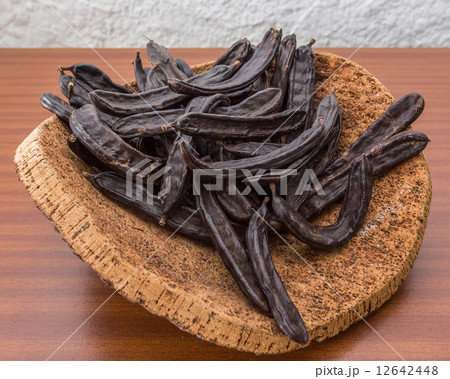Carob pods on cortical stand. On the table. Carob pods on cortical stand. On the table. 12642448