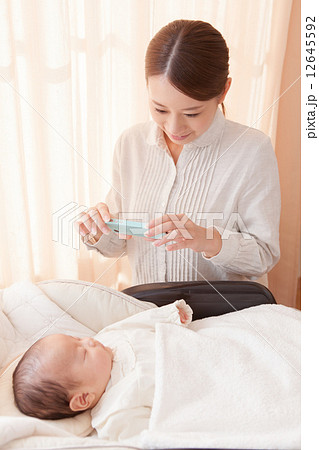 生後2ヶ月の赤ちゃんをスマホで撮影するママ 生後2ヶ月の赤ちゃんをスマホで撮影するママ 12645592