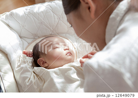 生後２ヶ月の赤ちゃんと寝顔を見つめる母親の写真素材