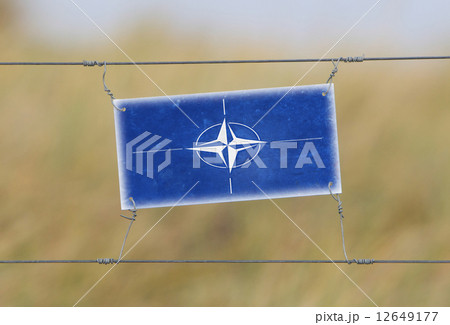 Border fence - Old plastic sign with a flag 12649177