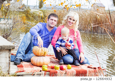 Young family near lake with pumpkins, autumn time 12664932