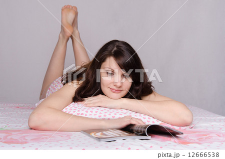 Girl infatuated interesting article while lying in bed 12666538