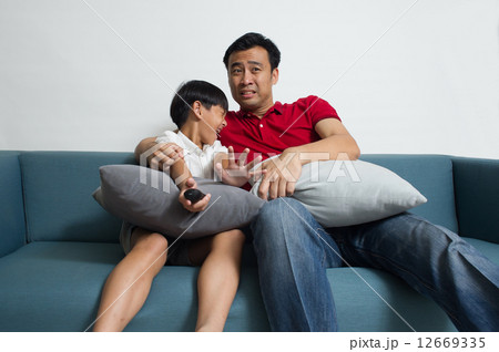 Asian Father and son watching sport supporting different team in the living room 12669335