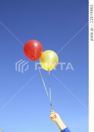 red and gold air helium balloons in hand on blue sky background 12679863