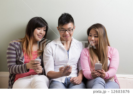 Happy Asian students using their cell phones. Happy Asian students using their cell phones. 12683876