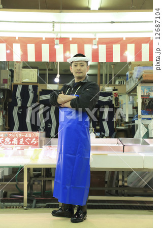 鮮魚店の前に腕組みをして立つ男性 12687104