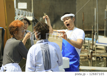 屋外で魚を売る鮮魚店店員と女性客 12687105