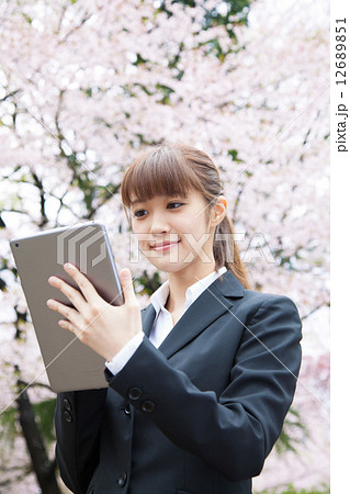 桜の前のスーツ姿の女性の写真素材
