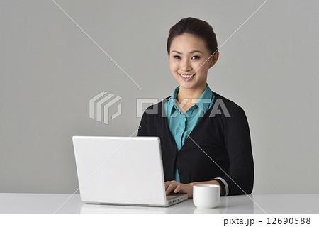 an confident asian office lady sitting in front of her desk 12690588