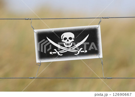 Border fence - Old plastic sign with a flag 12690667