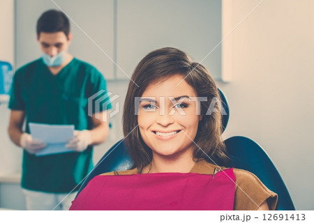 Man dentist reading woman patient's card 12691413